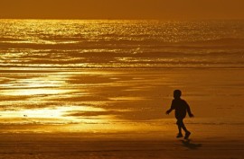 child on a beach at sunset