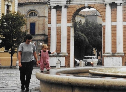 Toddler walking on a fountain wall next to her mother