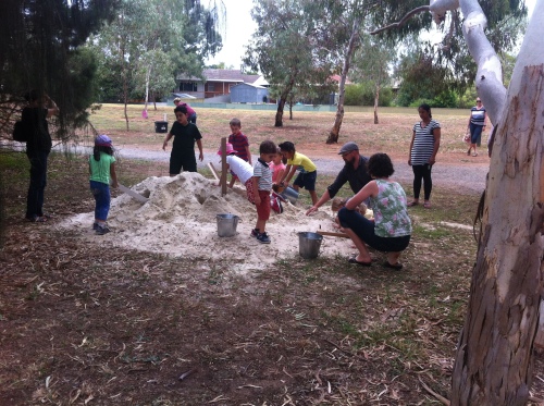 Children playing with a pile of sand in a park